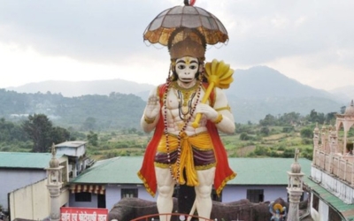 Giant statue of Lord Hanuman holding a mace with a mountain backdrop